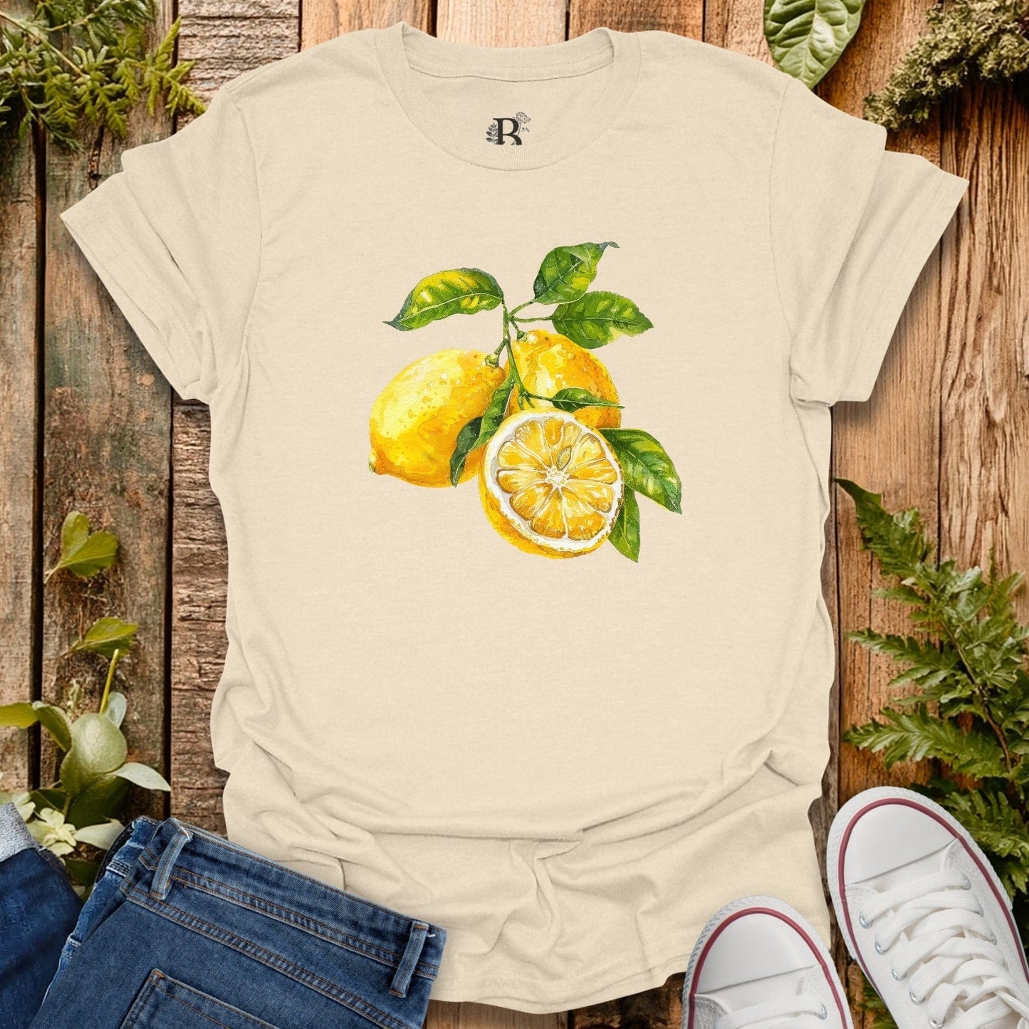Beige t-shirt with lemon design on a wooden surface with plants.