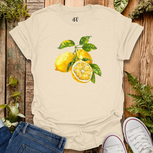 Beige t-shirt with lemon design on a wooden surface with plants.