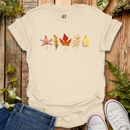 Beige t-shirt with leaf design on a wooden surface with plants