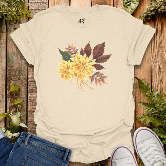 Beige t-shirt with floral design on a wooden surface with plants.