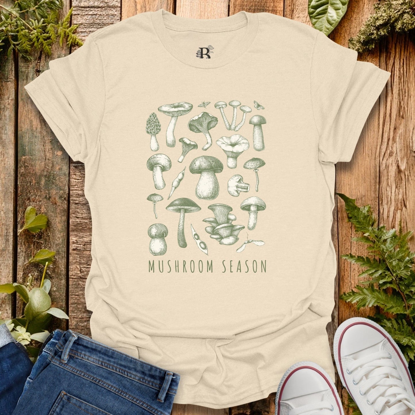 Beige t-shirt with mushroom design and 'Mushroom Season' text on a wooden background