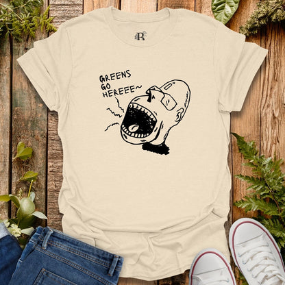 Beige t-shirt with graphic design and text on a wooden surface with plants.