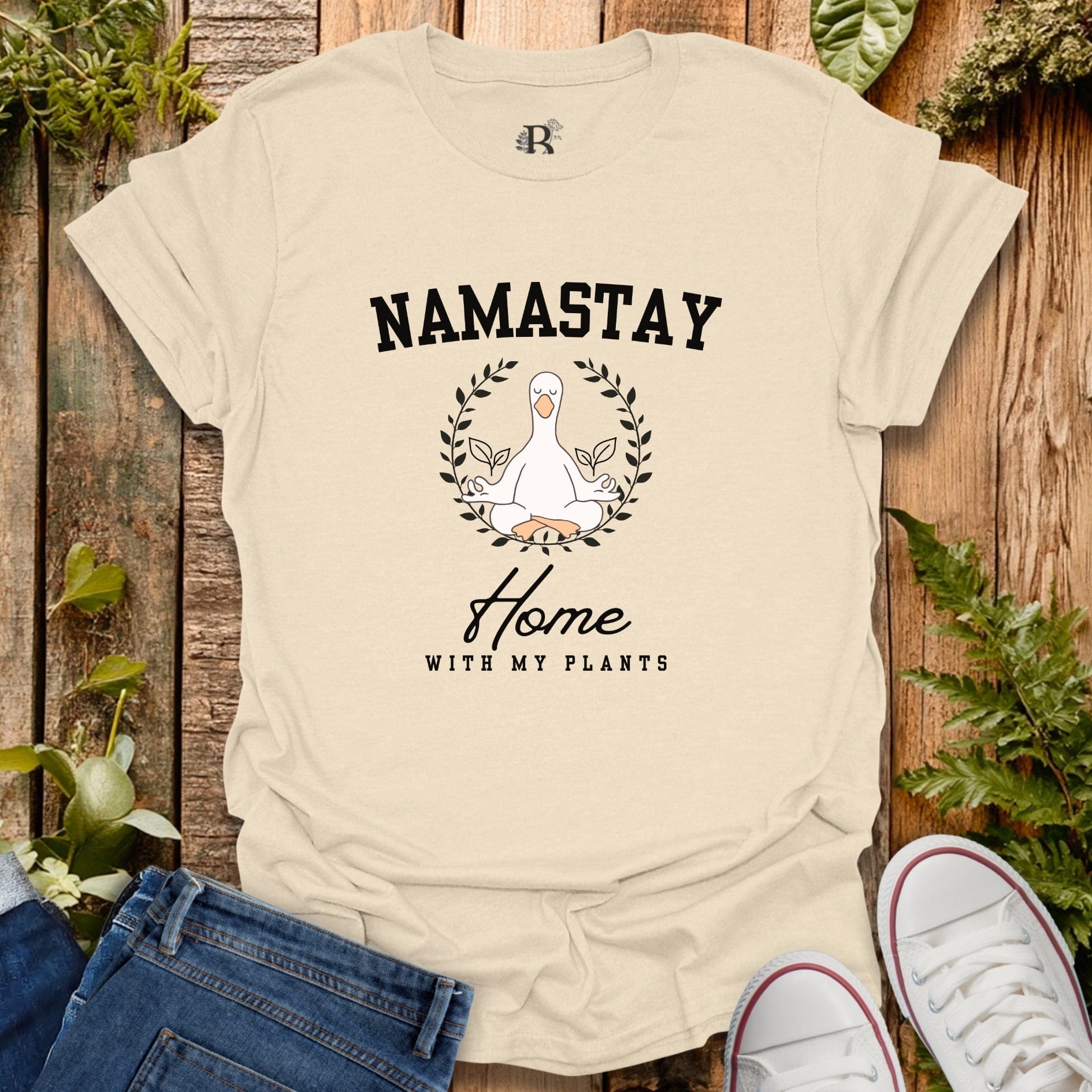 Beige t-shirt with 'Namastay Home with My Plants' design on a wooden background