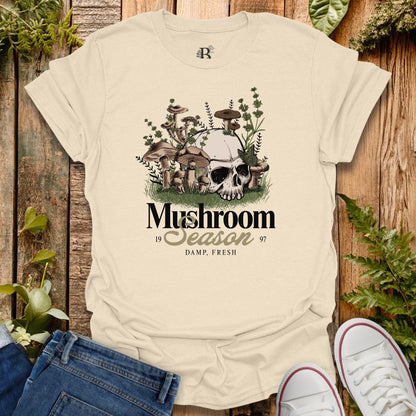 Beige t-shirt with mushroom graphic and text on a wooden background