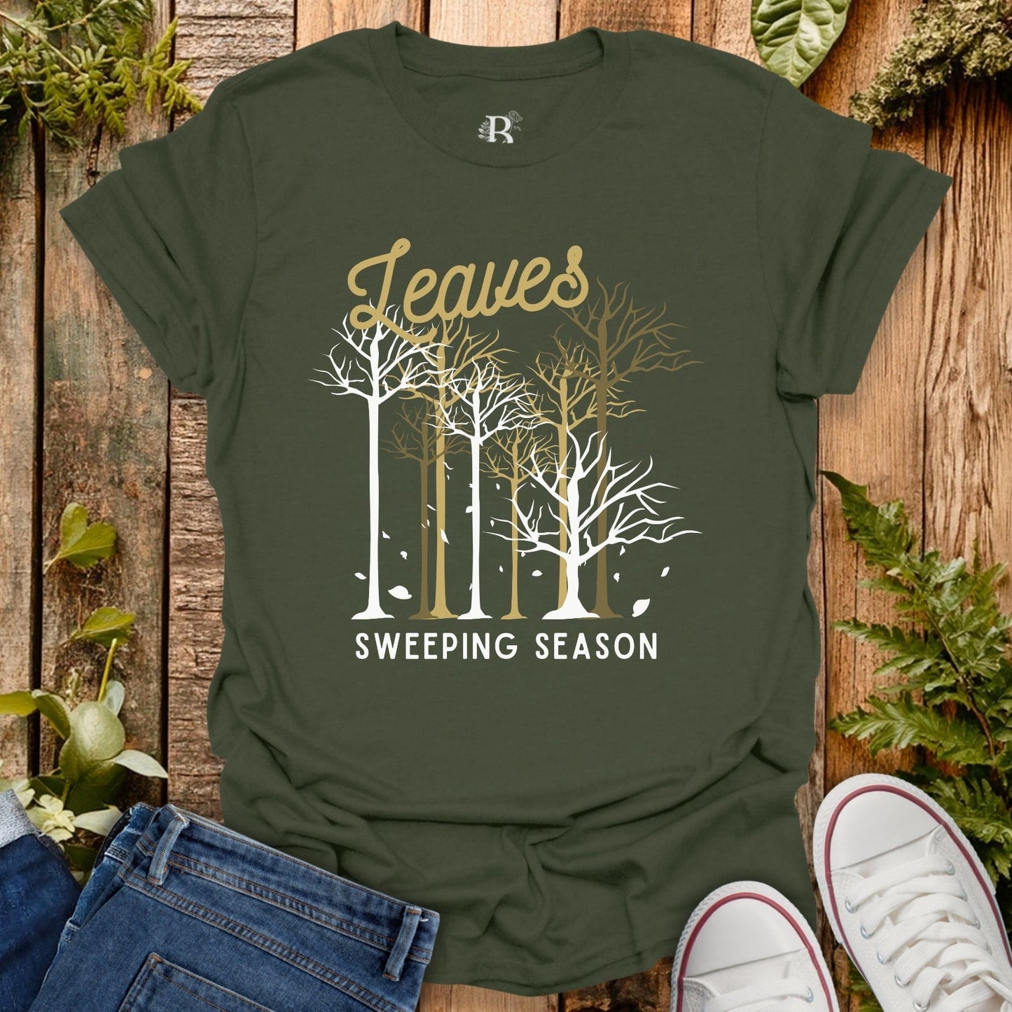 Green t-shirt with 'Leaves Sweeping Season' design on a wooden background