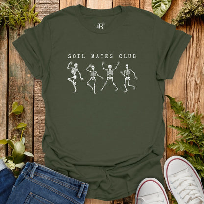 Green t-shirt with skeleton design and 'Soil Mates Club' text on a wooden background