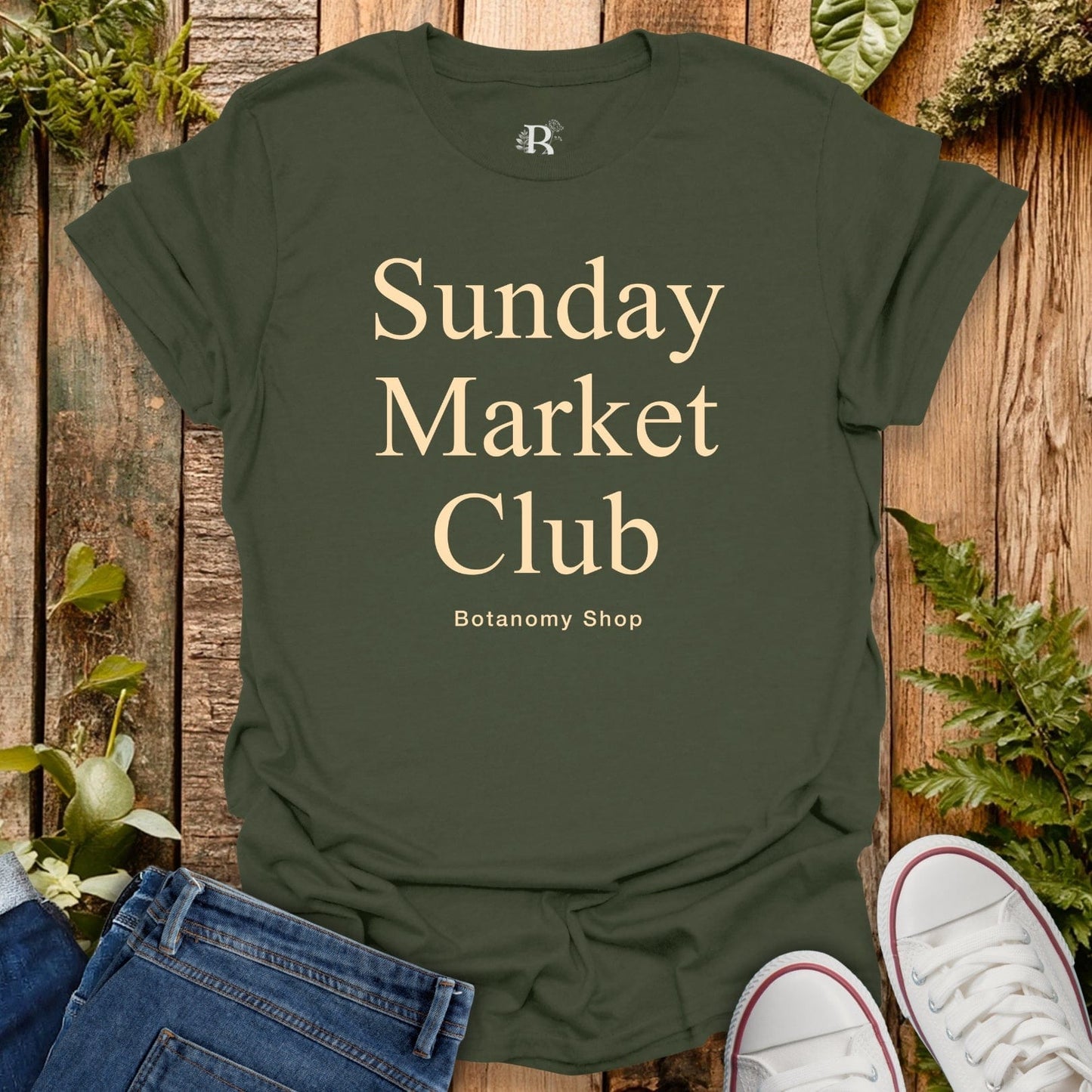 Green t-shirt with 'Sunday Market Club' text on a wooden background