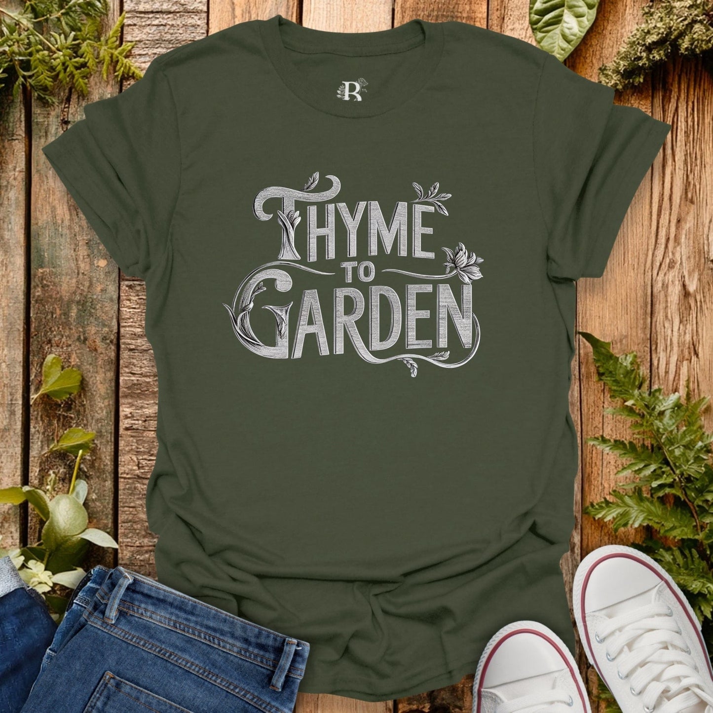 Green t-shirt with 'Thyme to Garden' text on a wooden background with plants.