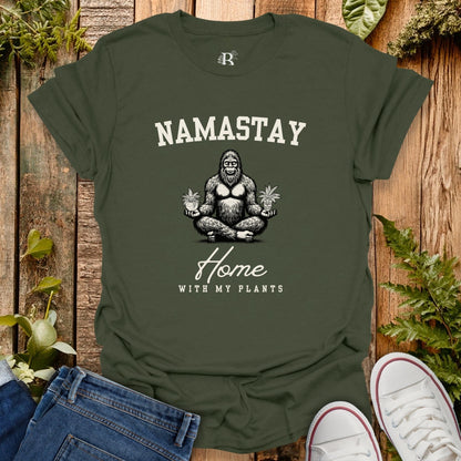 Green t-shirt with 'Namastay Home with My Plants' design on a wooden background