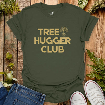 Green t-shirt with 'Tree Hugger Club' text on a wooden background with plants.
