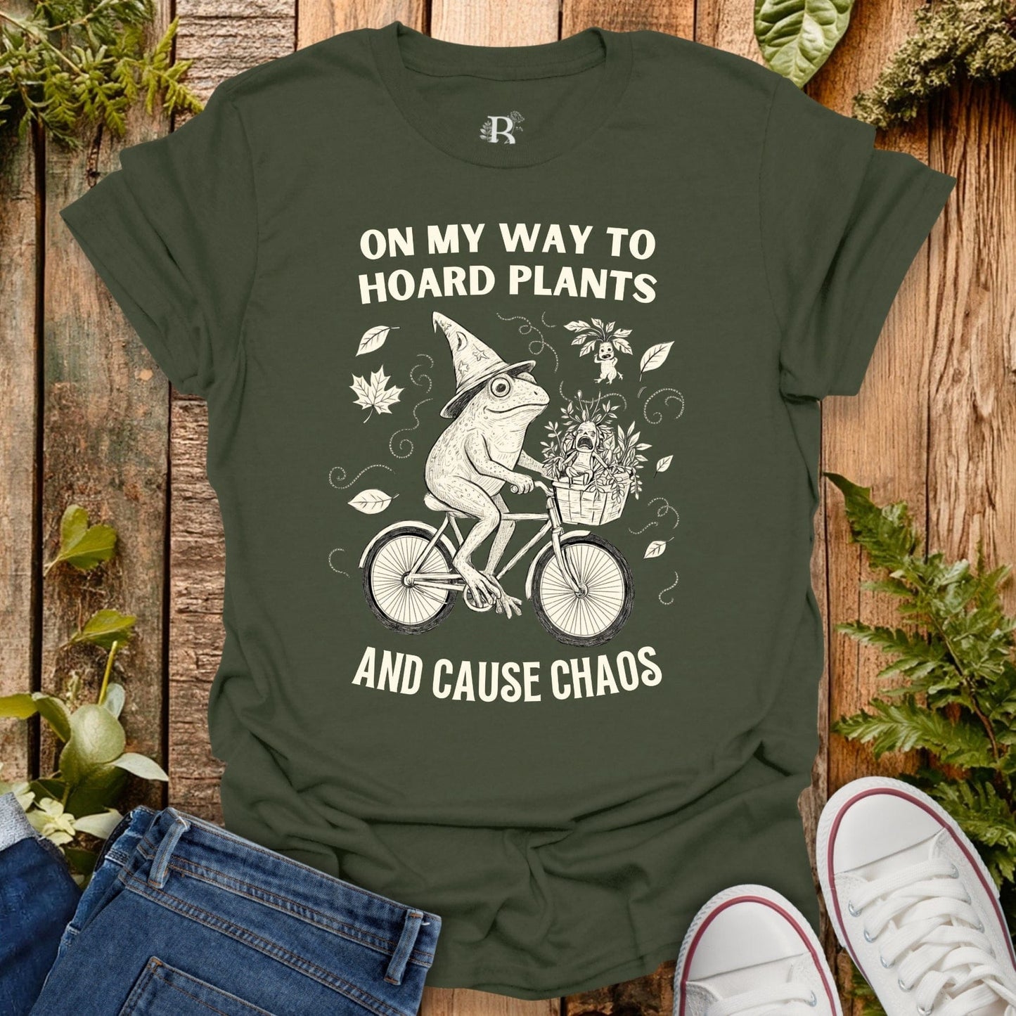 Green t-shirt with a frog graphic and text on a wooden background with plants.