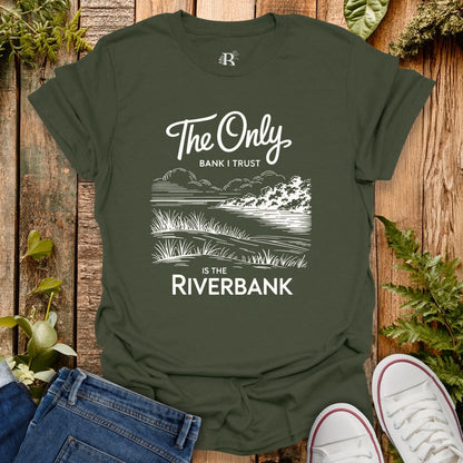 Green t-shirt with nature-themed design and text on a wooden surface with plants.