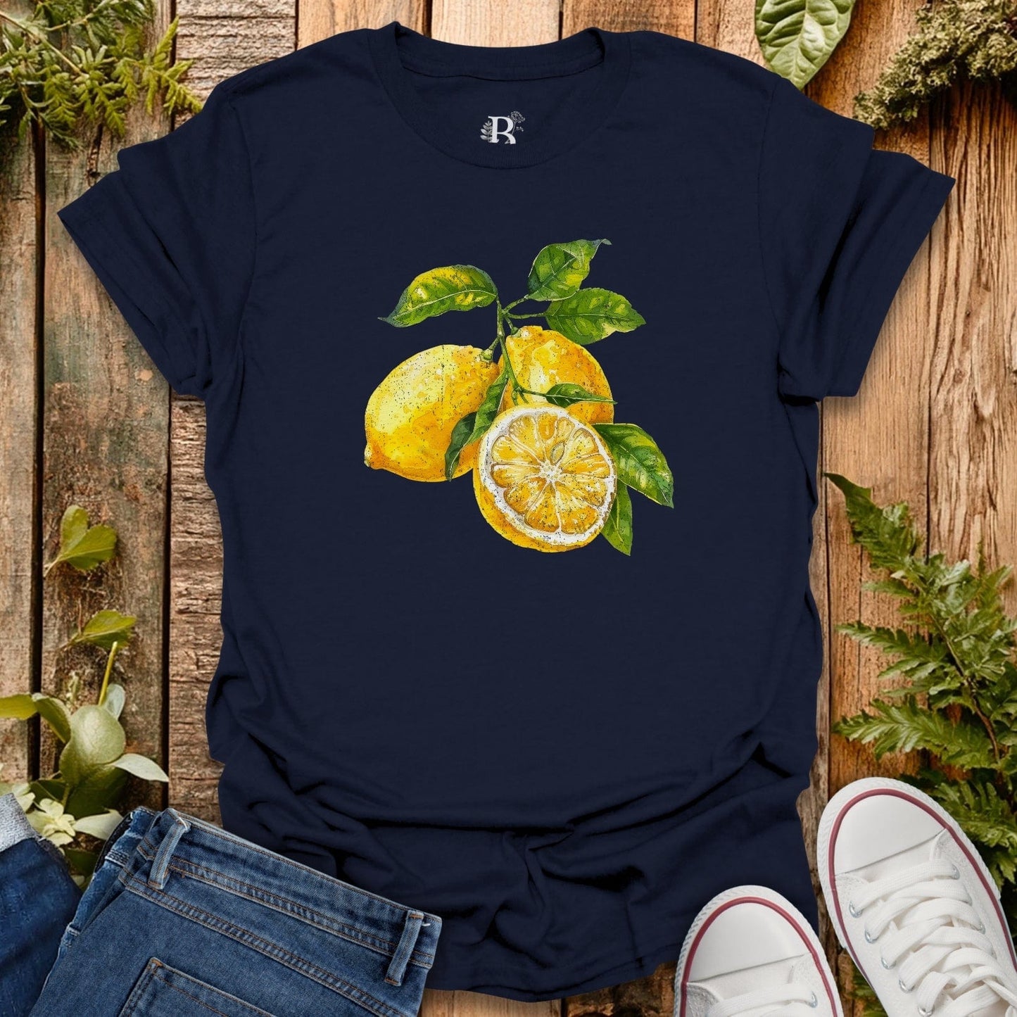 Navy blue t-shirt with lemon design on a wooden surface with jeans and white sneakers.