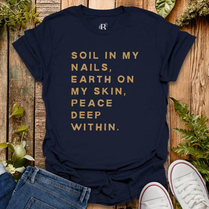 Navy blue t-shirt with gold text on a wooden surface with plants