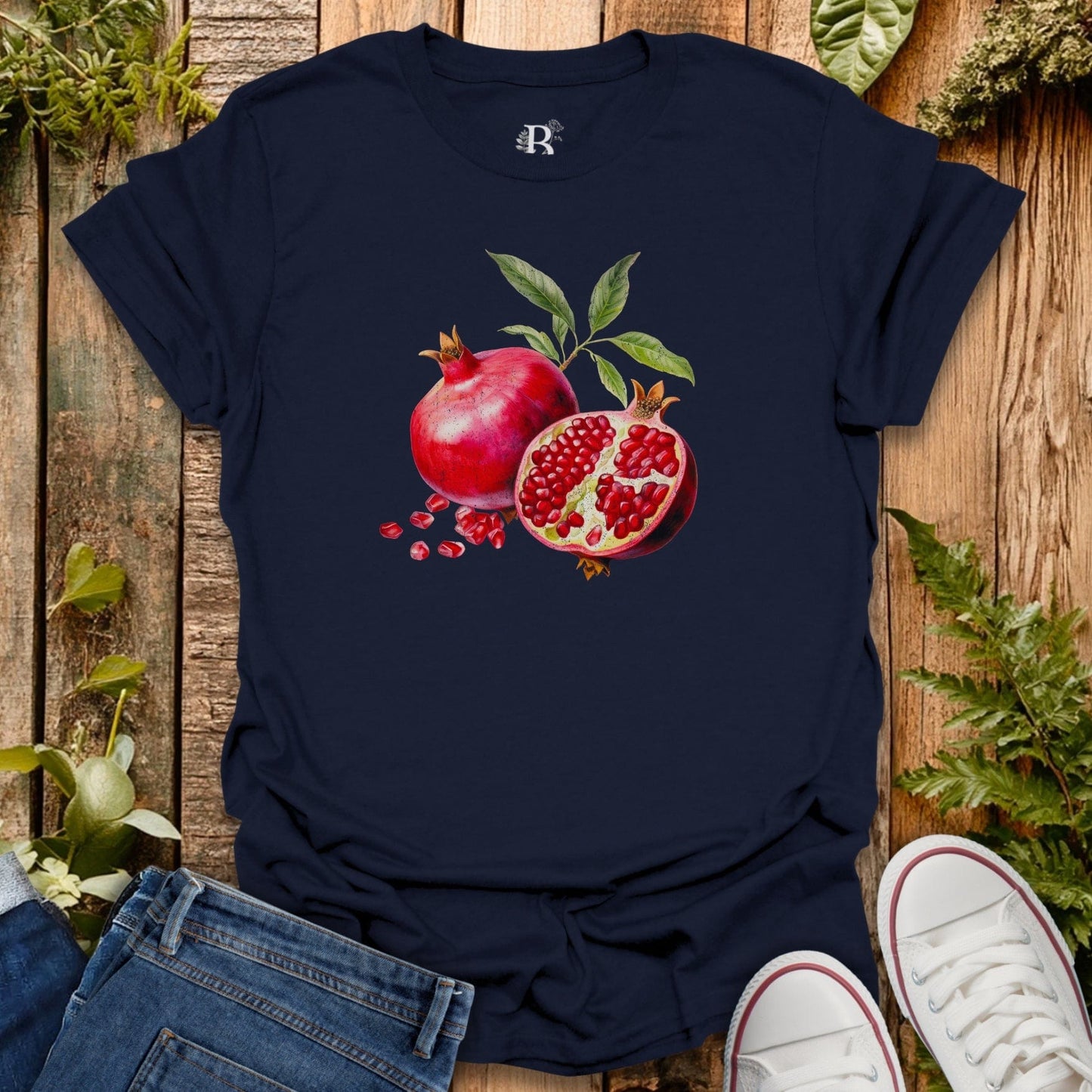 Navy blue t-shirt with pomegranate design on a wooden surface with plants.