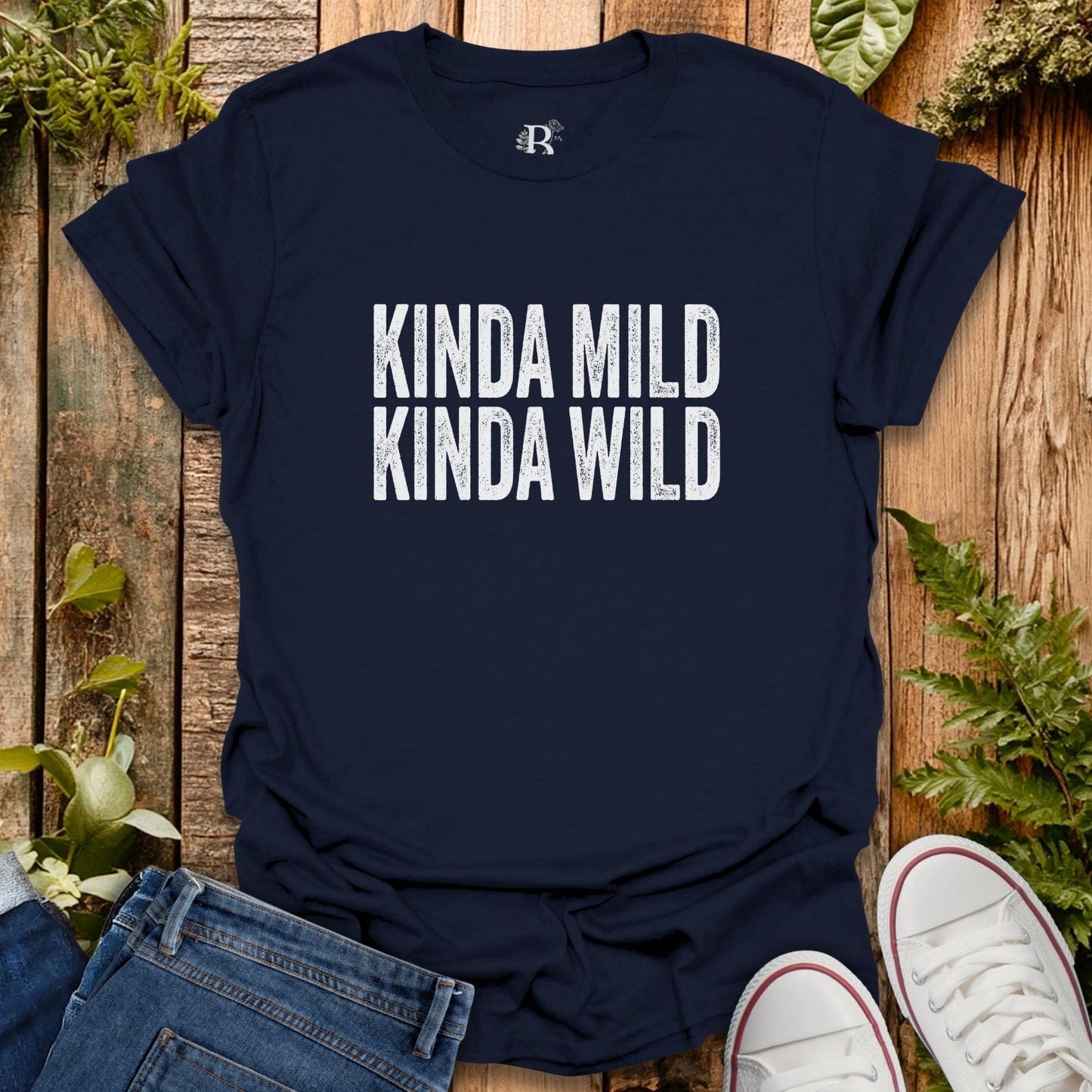 Navy blue t-shirt with 'KINDA MILD KINDA WILD' text on a wooden surface with jeans and sneakers.
