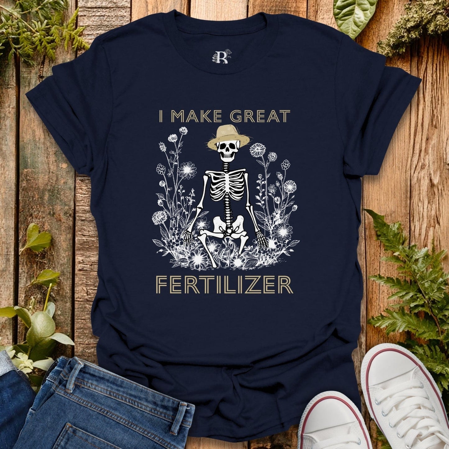 Navy blue t-shirt with skeleton graphic and text on a wooden surface with plants.