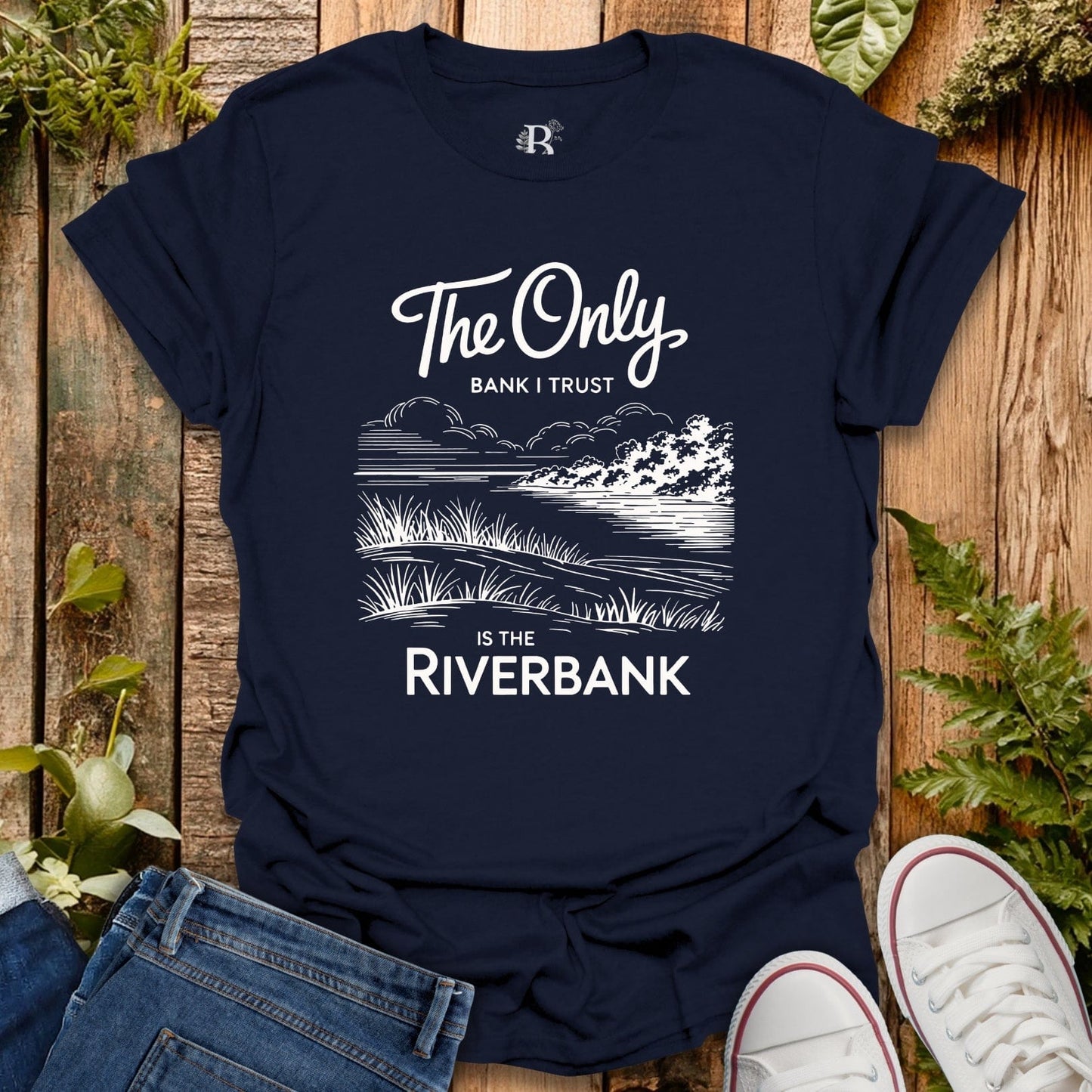 Navy blue t-shirt with white graphic and text on a wooden surface with plants.