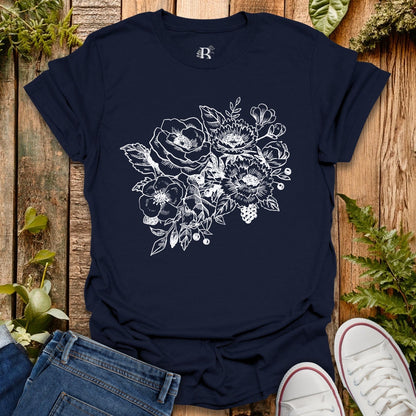 Navy blue t-shirt with floral design on a wooden surface with jeans and sneakers.