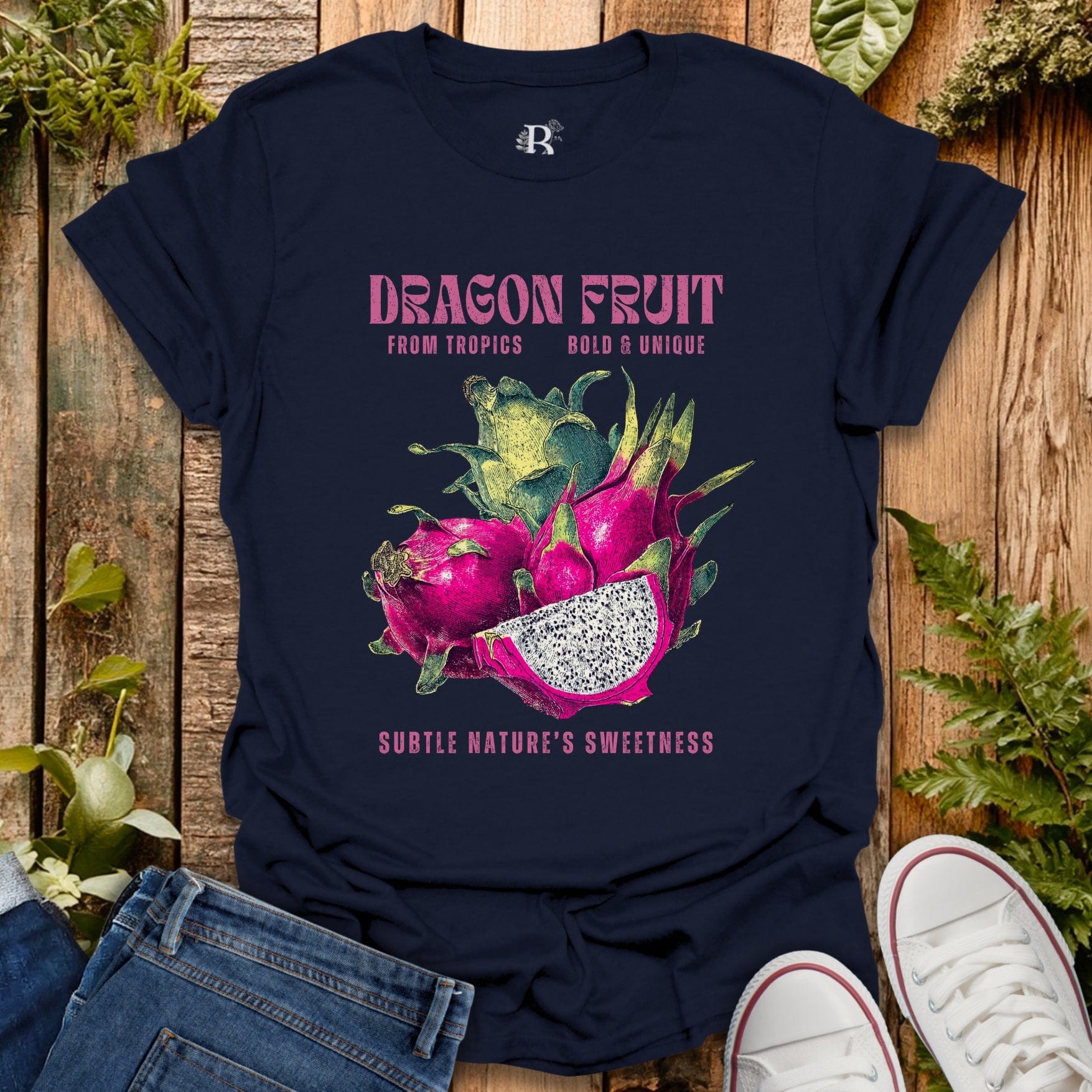 Navy blue t-shirt with dragon fruit graphic and text on a wooden surface with plants.