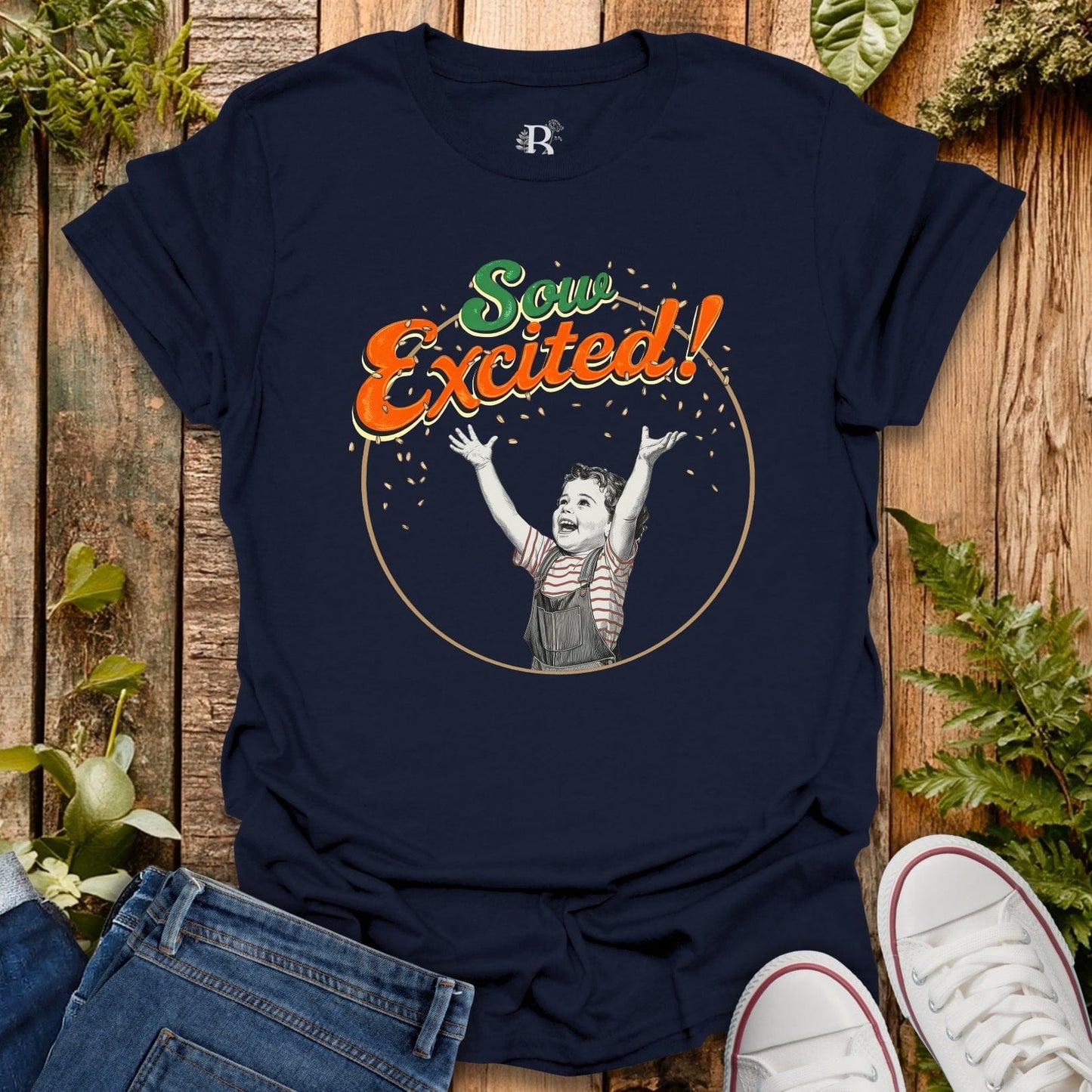 Navy blue t-shirt with 'Sow Excited!' graphic on a wooden surface with jeans and sneakers.
