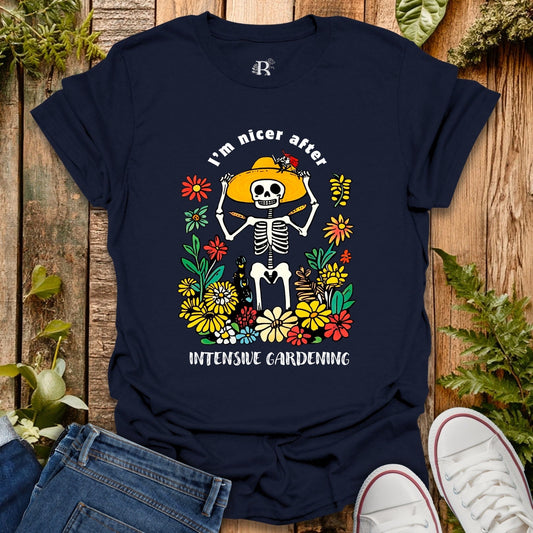 Navy blue t-shirt with skeleton and flowers design on a wooden surface with plants.