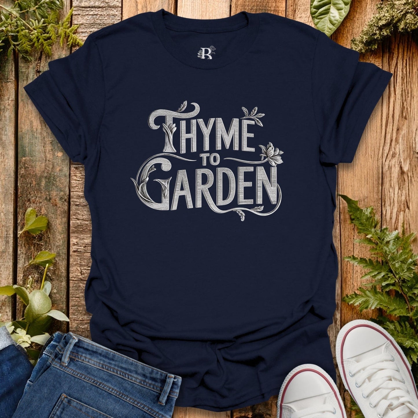 Navy blue t-shirt with 'Thyme to Garden' text on a wooden surface with plants.