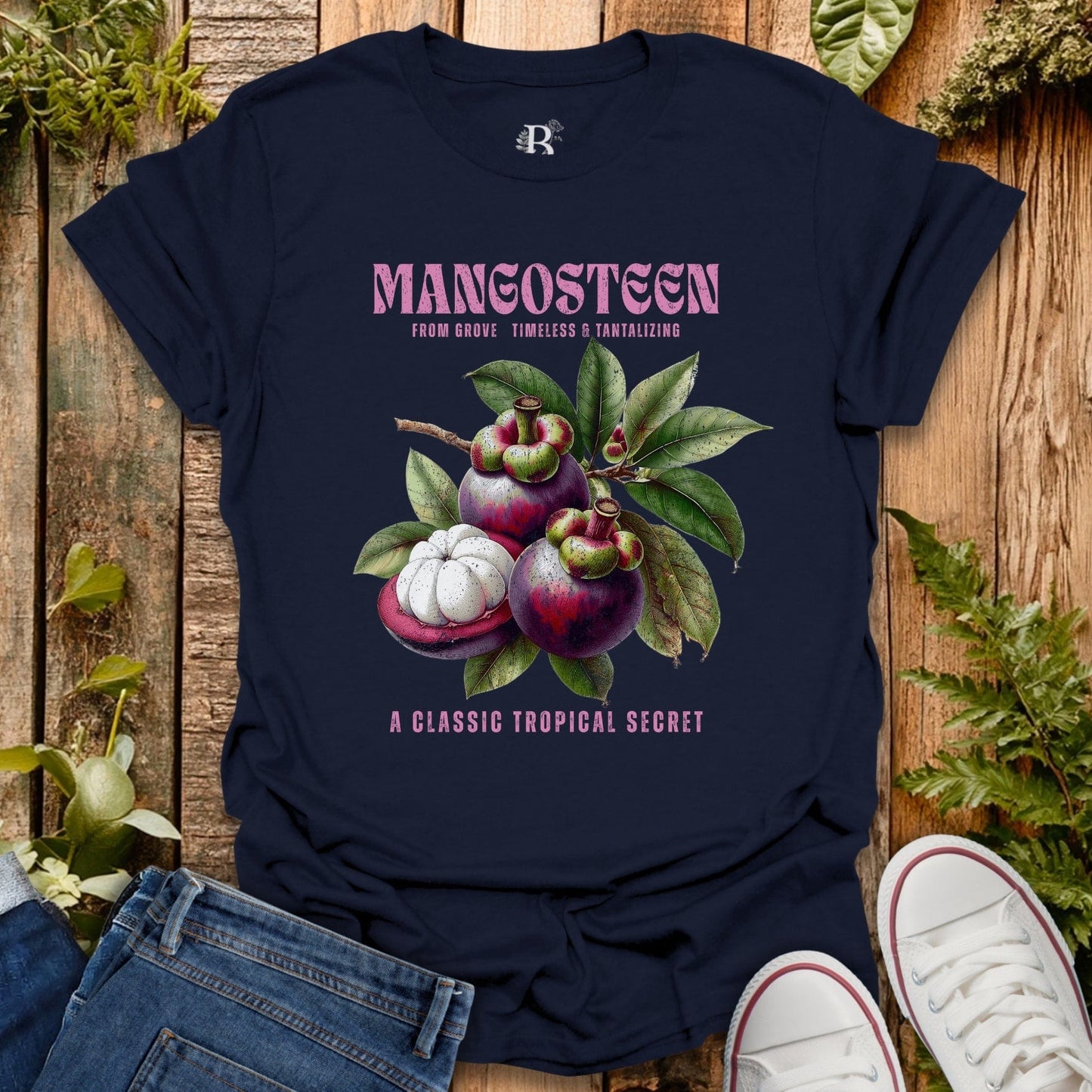 Navy blue t-shirt with mangosteen graphic and text on a wooden surface with plants.