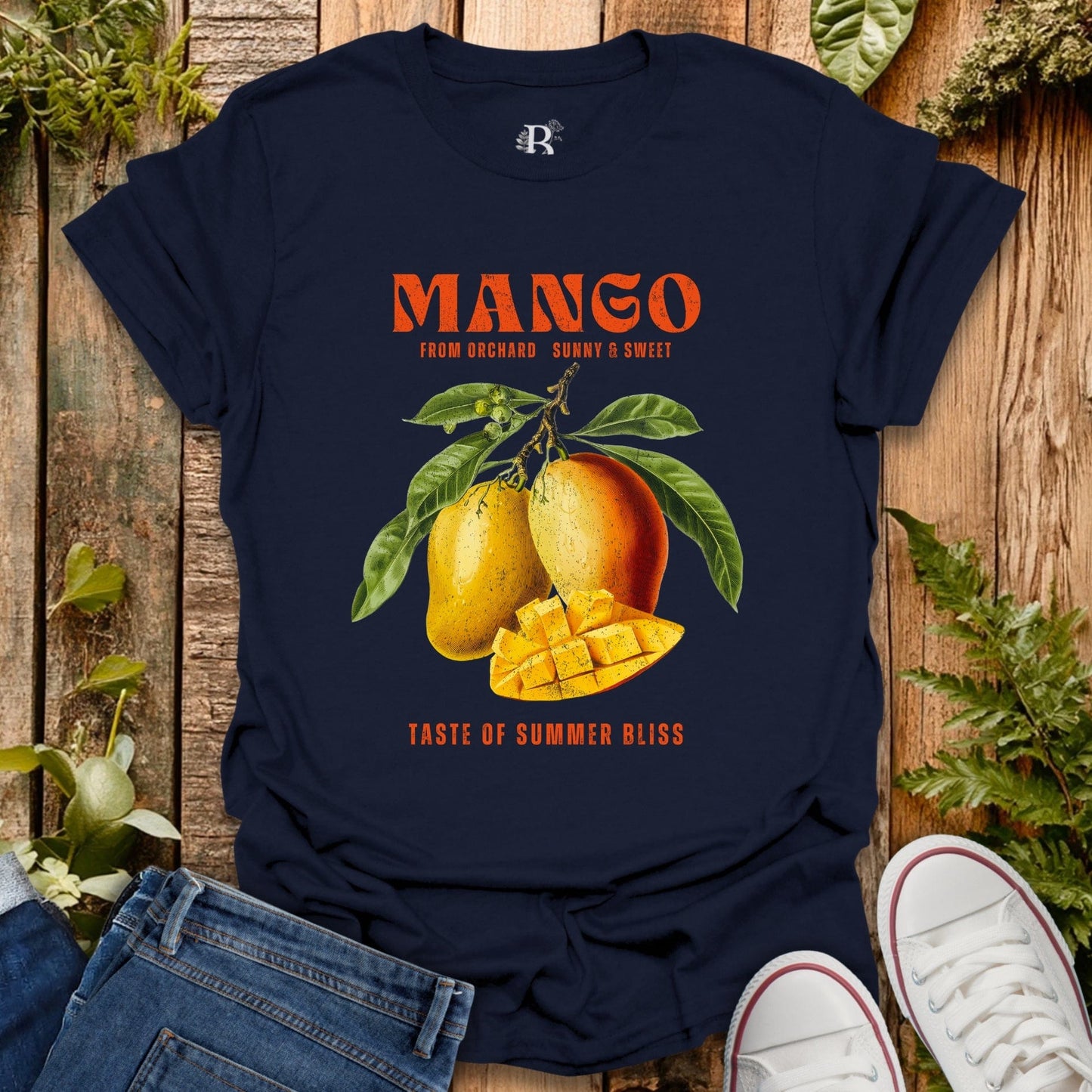 Navy blue t-shirt with mango graphic and text on a wooden surface with plants.