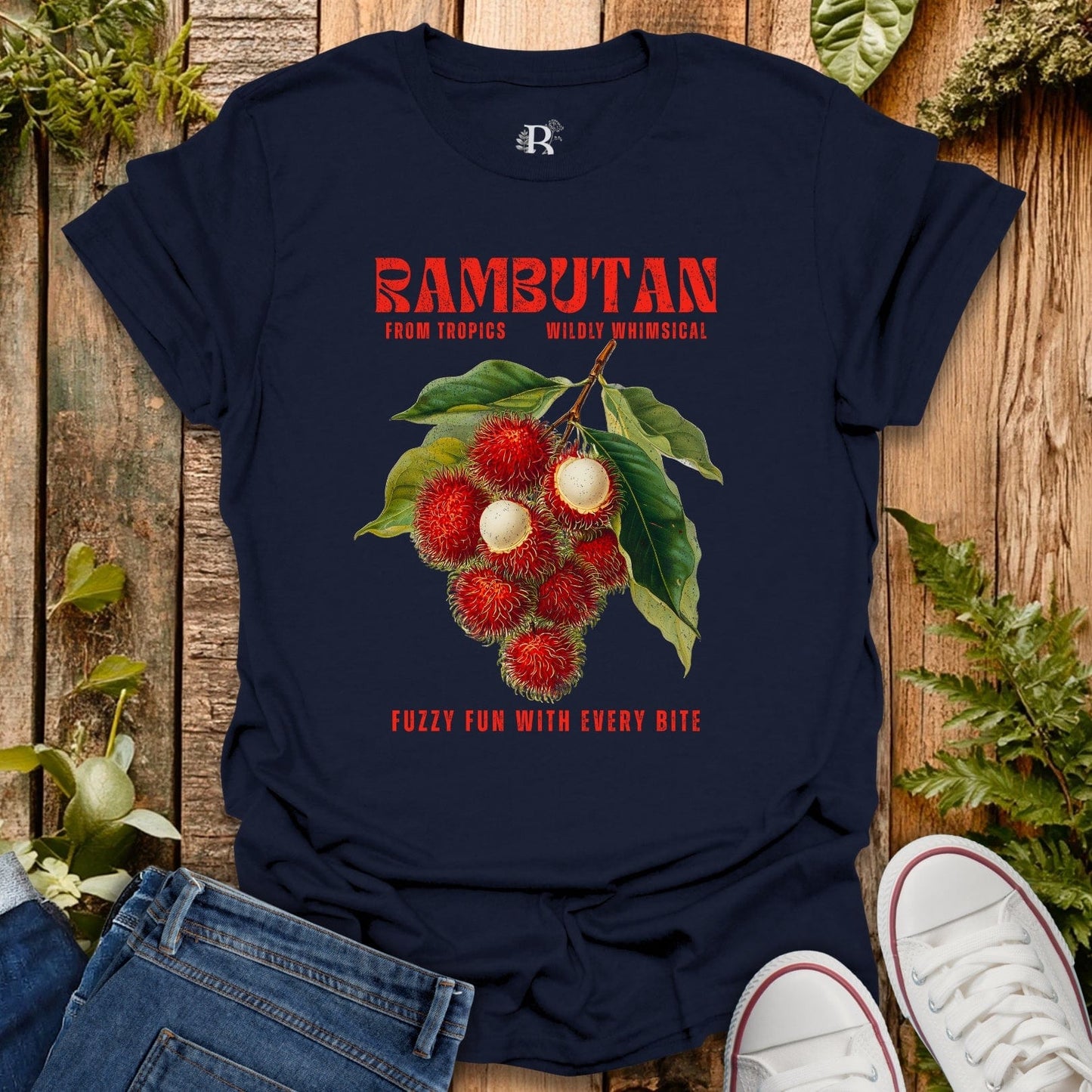Navy blue t-shirt with rambutan graphic and text on a wooden surface with plants.
