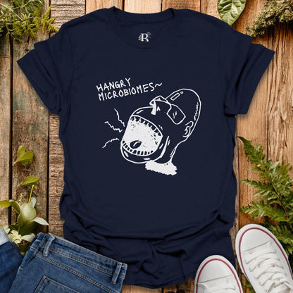 Navy blue t-shirt with a graphic design and text on a wooden surface with plants.