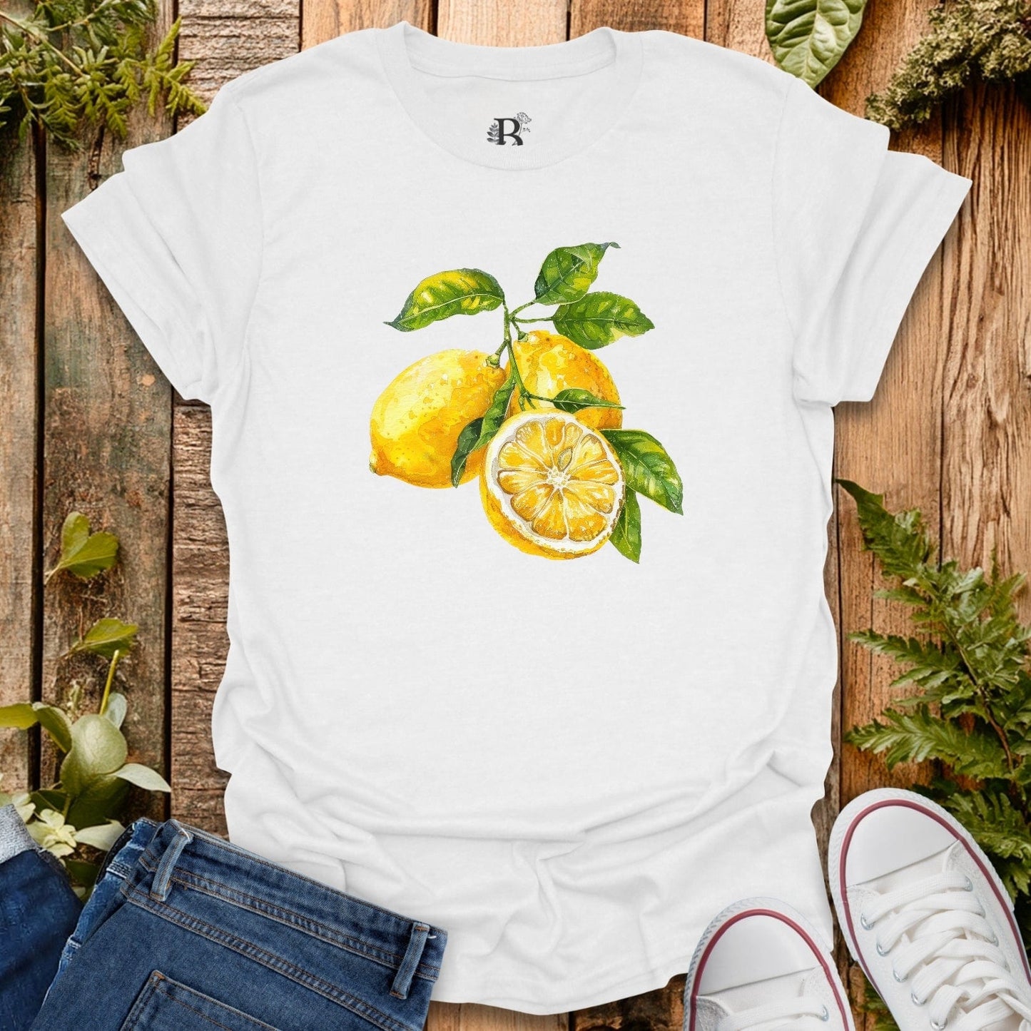 White t-shirt with lemon design on a wooden surface with plants