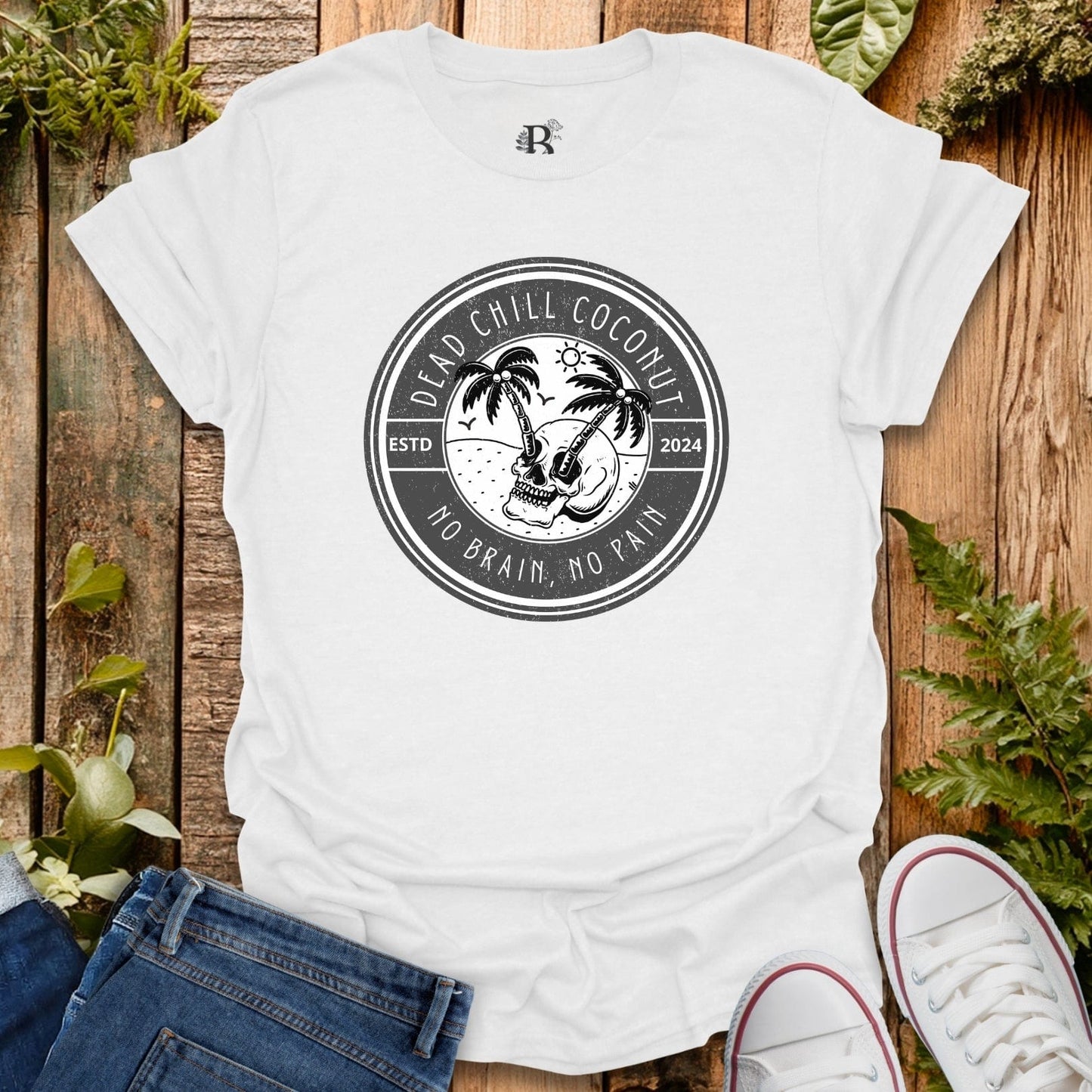 White t-shirt with a black graphic design on a wooden surface with plants.