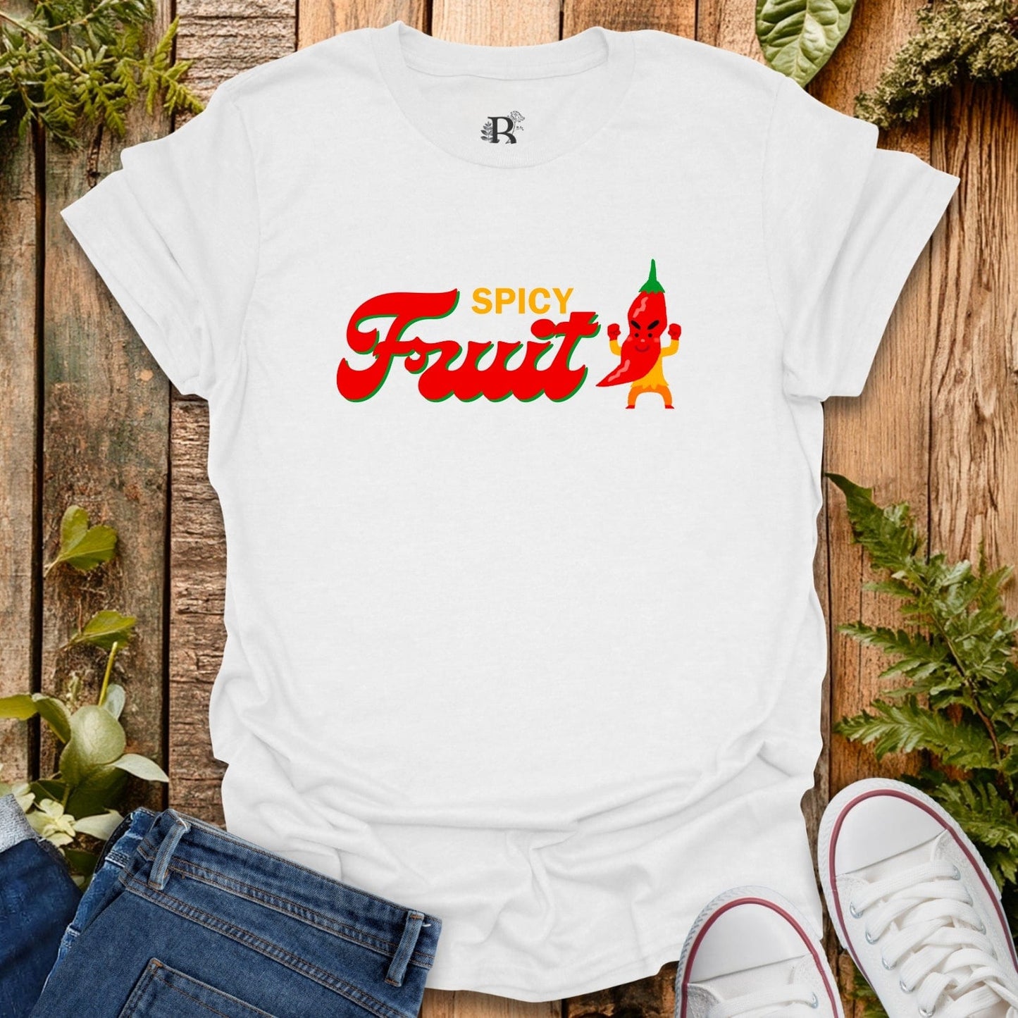 White t-shirt with 'Spicy Fruit' graphic design on a wooden surface with plants.