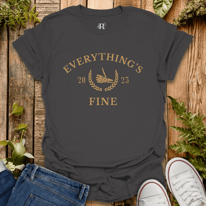 Black t-shirt with 'Everything's Fine' text on a wooden surface with jeans and white sneakers.