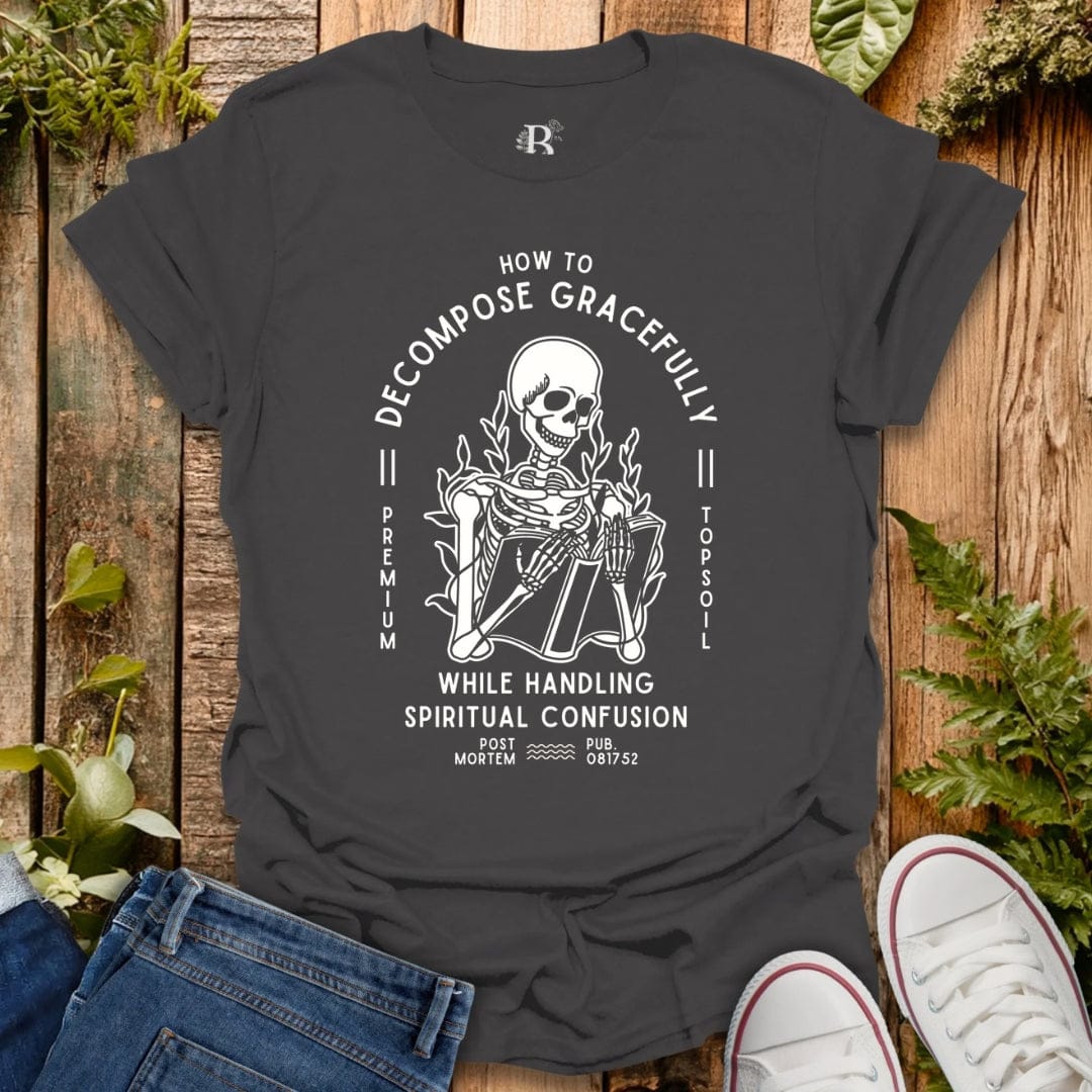 Gray t-shirt with a skeleton graphic and text on a wooden surface with plants.