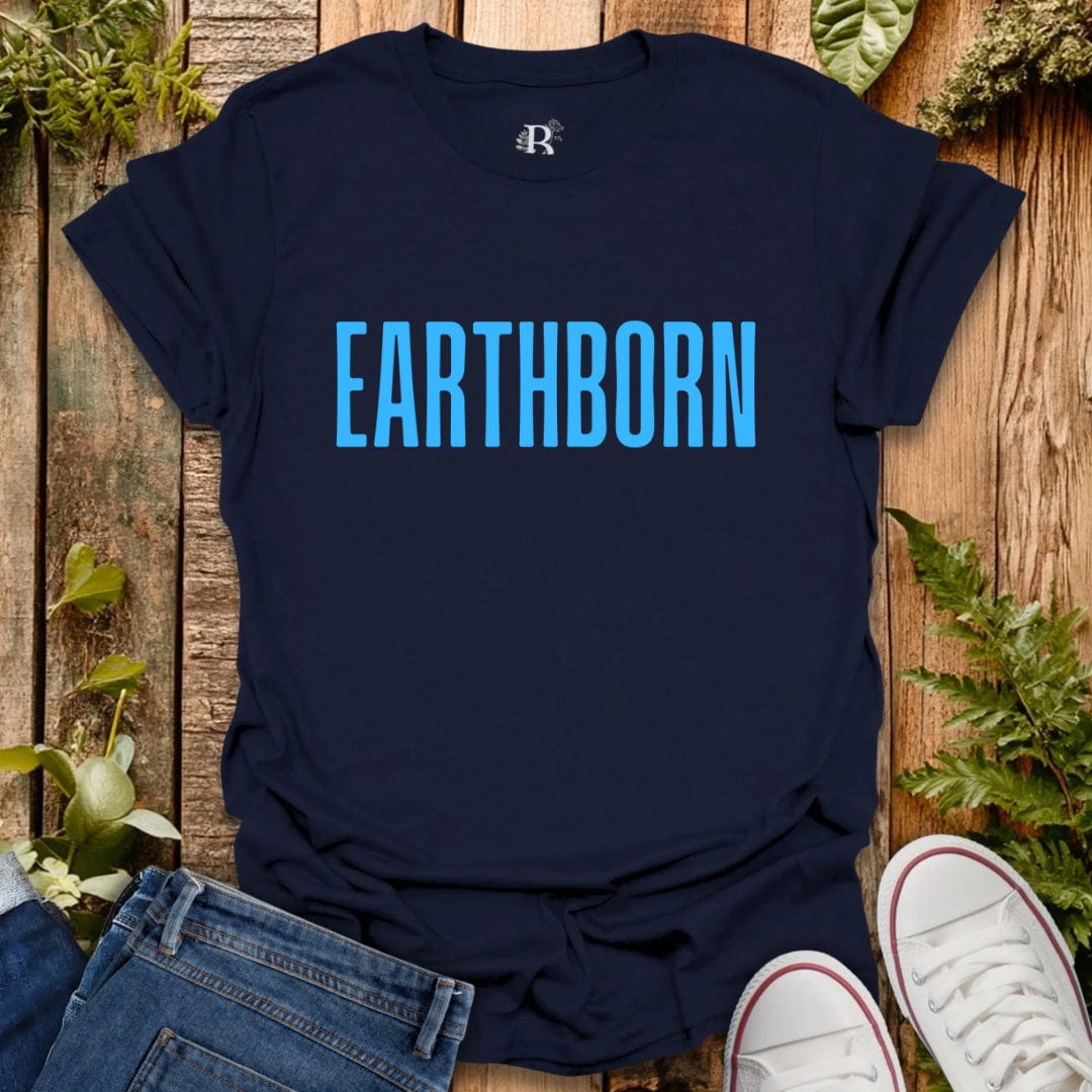 Navy blue t-shirt with 'EARTHBORN' text on a wooden surface with plants.