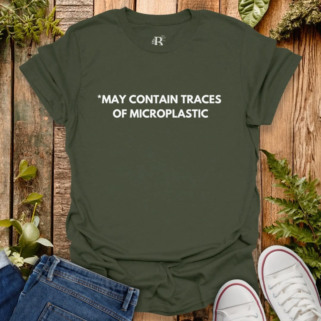 Green t-shirt with text 'MAY CONTAIN TRACES OF MICROPLASTIC' on a wooden background with jeans and sneakers.