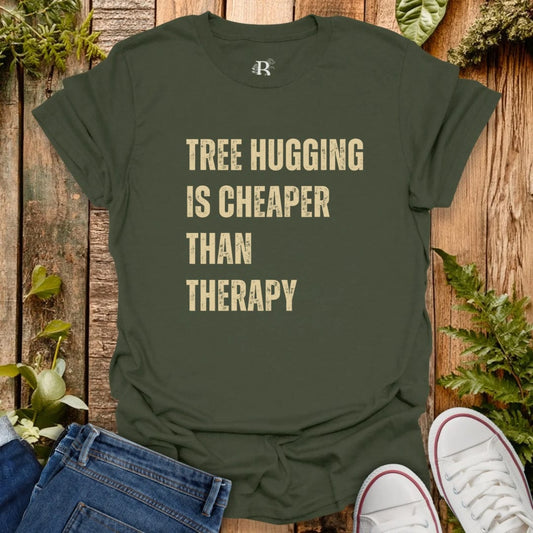 Green t-shirt with 'Tree Hugging is Cheaper Than Therapy' text on a wooden background with plants.
