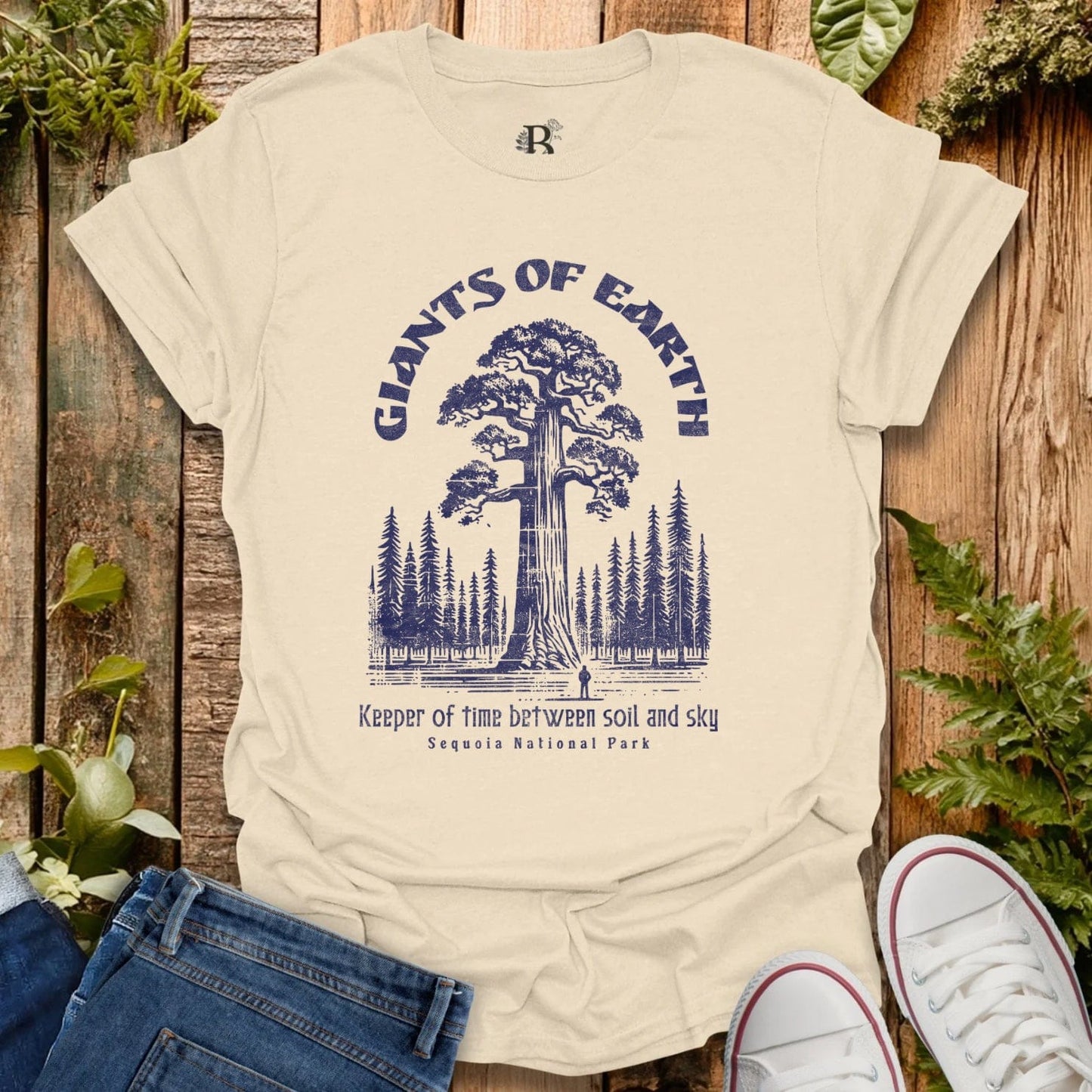 Beige t-shirt with 'Giants of Earth' graphic design on a wooden background