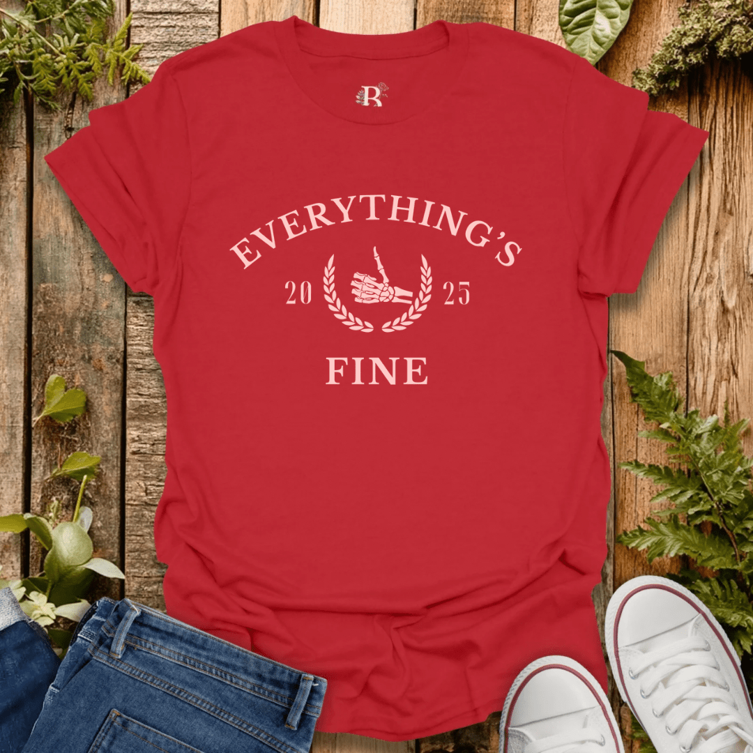 Red t-shirt with 'Everything's Fine' text on a wooden surface with jeans and white sneakers.