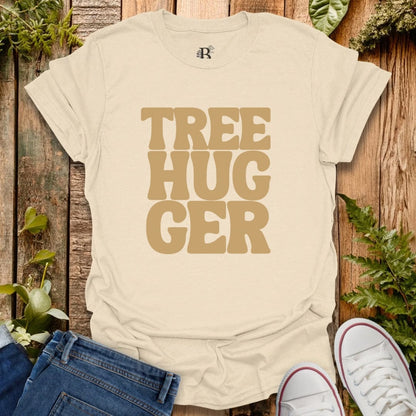 Beige t-shirt with 'TREE HUGGER' text on a wooden background with plants.
