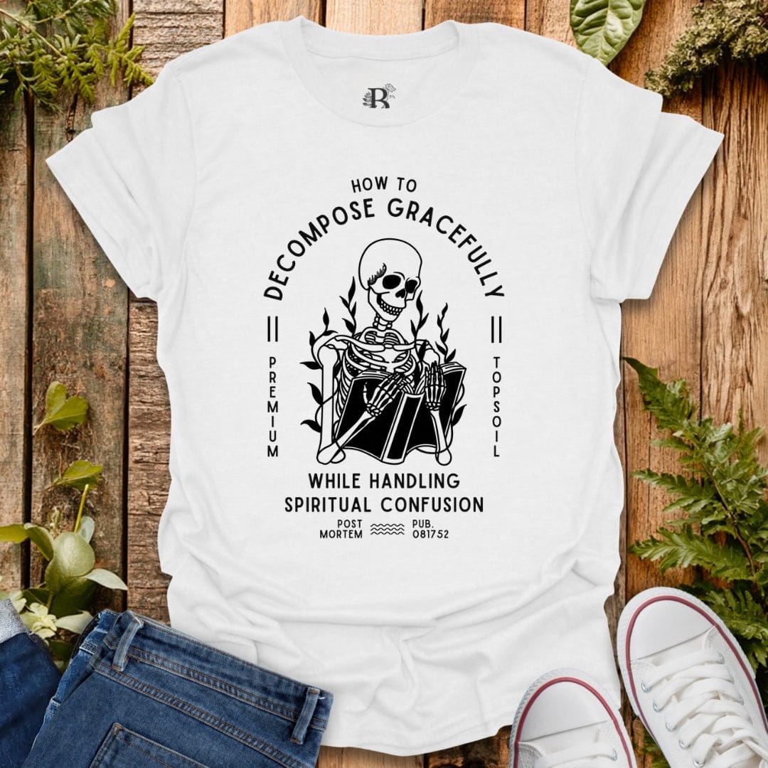 White t-shirt with a skeleton graphic and text on a wooden surface with plants.