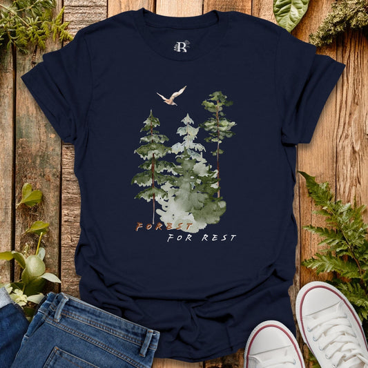 Navy blue t-shirt with forest design and text on a wooden surface with plants.